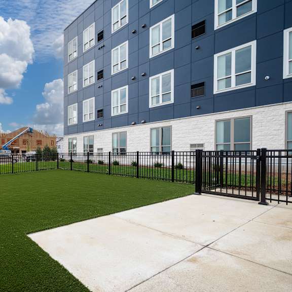 the yard of an apartment building with a green lawn and a fence at the landing at amber fields apartments, rosemount