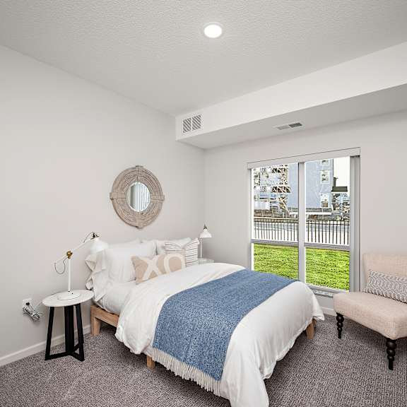 a bedroom with a large bed and a chair. at the landing at amber fields apartments, rosemount