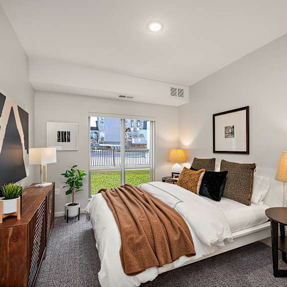 a bedroom with a large bed and a painting on the wall at the landing at amber fields apartments, minnesota