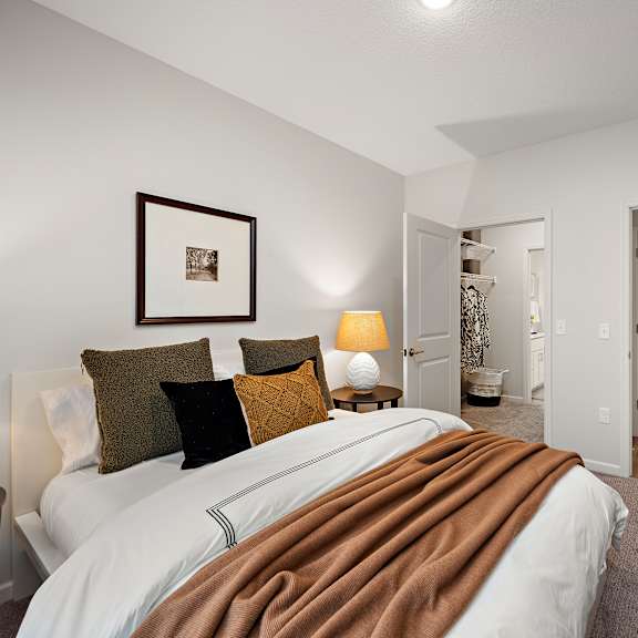 a bedroom with a large bed and a bathroom at the landing at amber fields apartments, rosemount, 55068