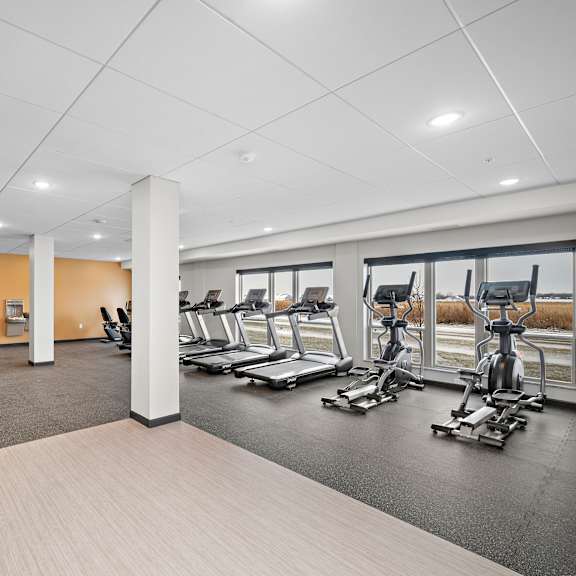 a gym with a variety of equipment including treadmills, stationary bikes, and weight machines at the landing at amber fields apartments, rosemount, mn, 55068