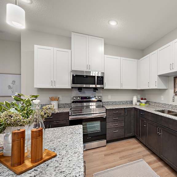 a kitchen with white cabinets and granite counter tops and stainless steel appliances at the landing at amber fields apartments, rosemount, mn