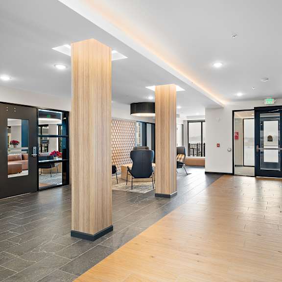 a hallway with a black chair and a wooden column at the landing at amber fields apartments, rosemount, 55068