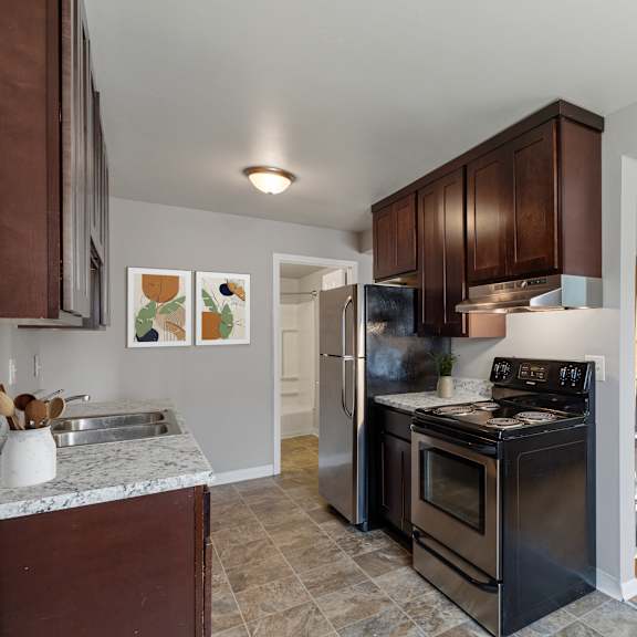 a kitchen with black appliances and a living room with a couch at ames lake neighborhood apartments, minnesota, 55106