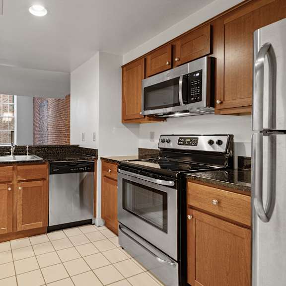 a kitchen with a black granite countertop and stainless steel appliances. at parkside apartments, st. paul