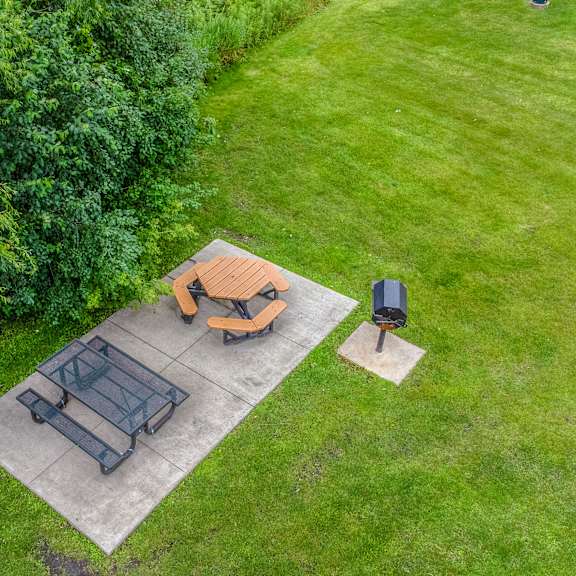 a backyard patio with a table and chairs and a fire pit at pheasant park apartments, minnesota, 55428-5401