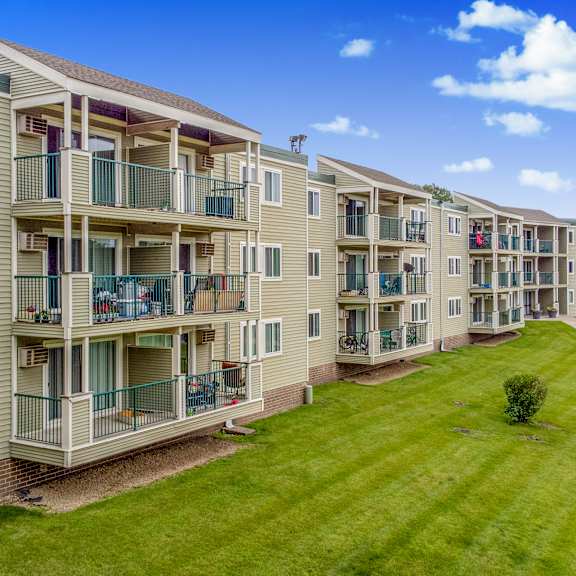 an exterior view of an apartment building with a green lawn at pheasant park apartments, new hope, mn