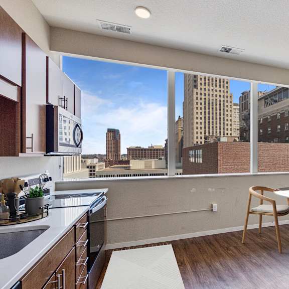 a kitchen with wooden cabinets and a view of the city at press house apartments, st paul, mn