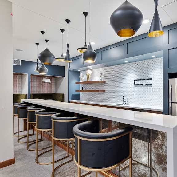 a large kitchen with a long counter top and a row of bar chairs at press house apartments, minnesota, 55101