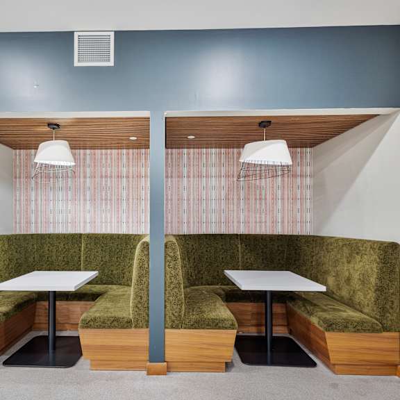 a communal seating area with two tables and green couches at press house apartments, st paul, mn