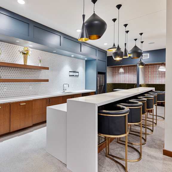 a communal kitchen with bar stools and blue and white tiles at press house apartments, st paul