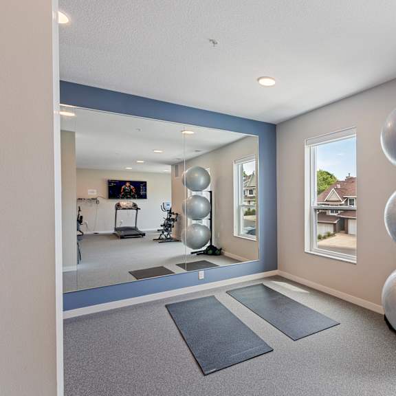 a fitness room with yoga mats and a large window at the quill 55+ apartments, minnesota