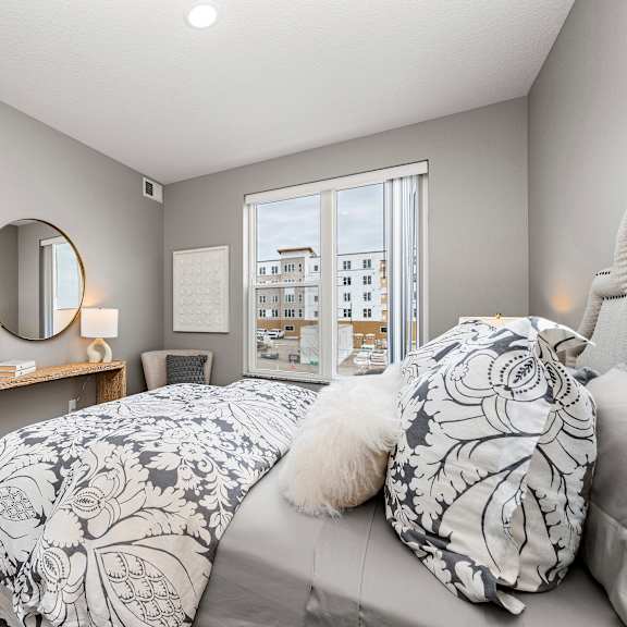bedroom with round mirror and patterned bedding at reserve at settlers ridge apartments, woodbury, mn