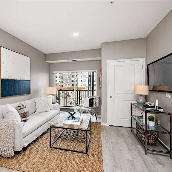 living room with balcony access and neutral furnishings at reserve at settlers ridge apartments, woodbury