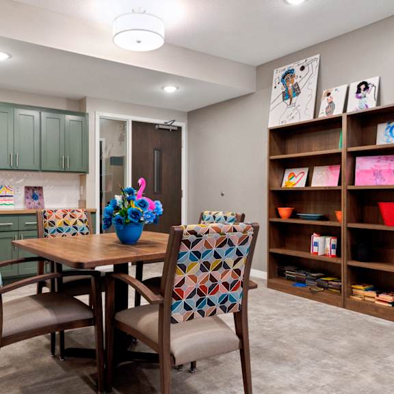 a kitchen with a table and chairs and a shelf with bowls on it at sonder point 50+ apartments, mn