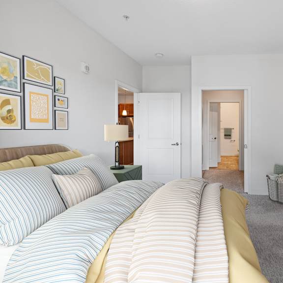 a bedroom with a bed and a dresser and a hallway to a bathroom