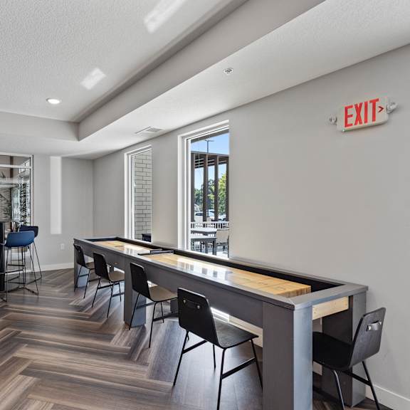 a game room with a shuffleboard table and chairs