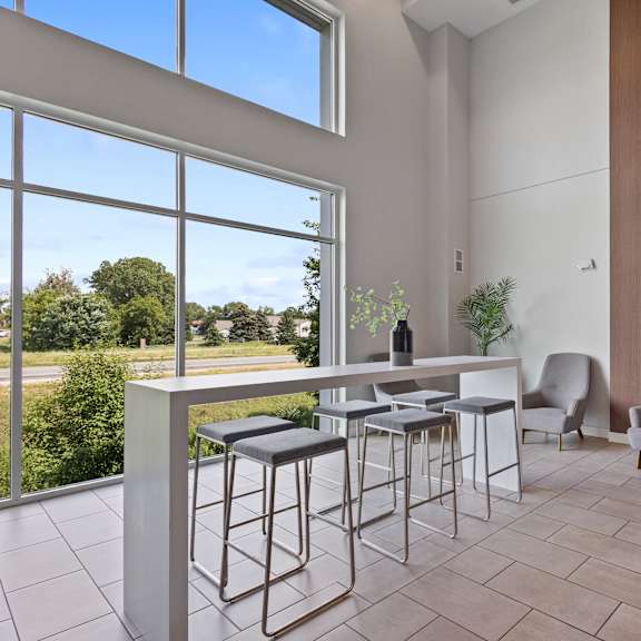 a bar with stools and chairs in a room with large windows