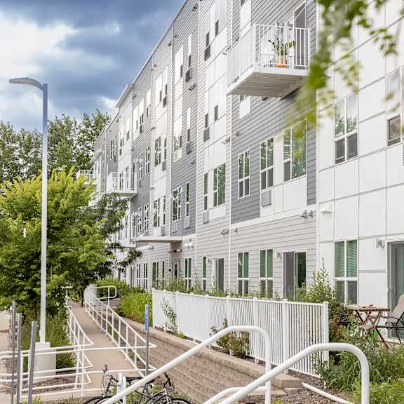 a large white apartment building with stairs and a fence at technology park apartments, minnesota, 55901