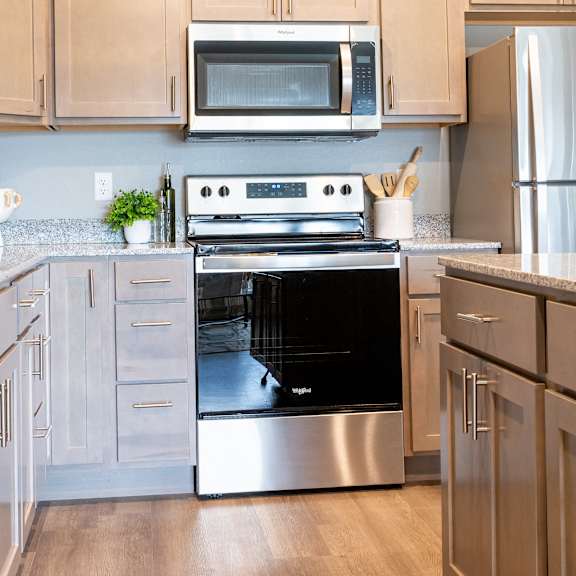 a modern kitchen with stainless steel appliances and white cabinets at technology park apartments, rochester, minnesota