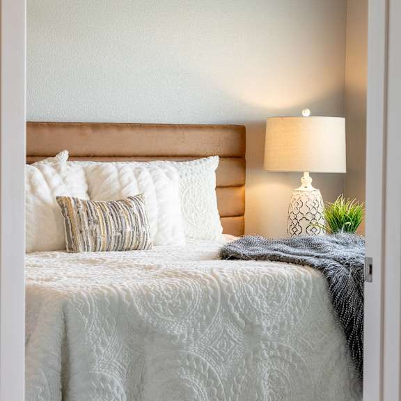 a bedroom with a bed and pillows and a lamp at technology park apartments, minnesota, 55901