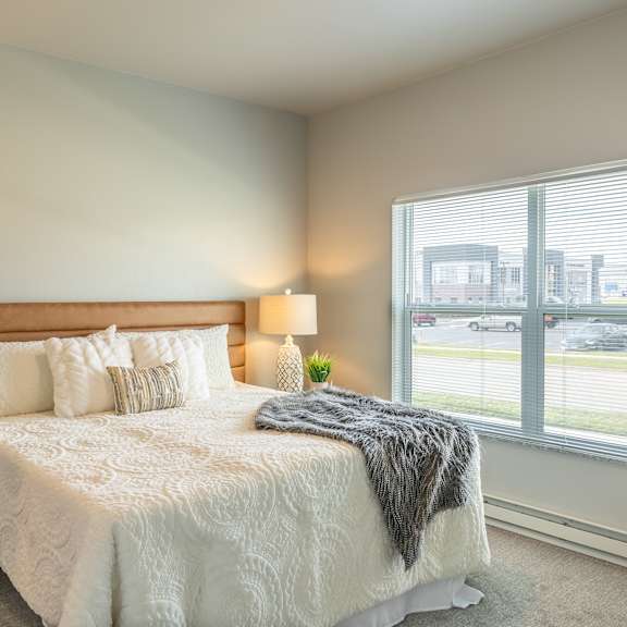 a bedroom with a bed and a large window at technology park apartments, rochester, mn, 55901