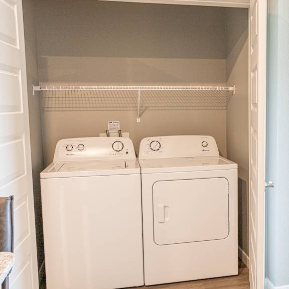 a room with a washer and dryer and a bedroom with a bed at technology park apartments, minnesota