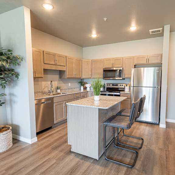 a kitchen with stainless steel appliances and a island with chairs at technology park apartments, rochester, mn