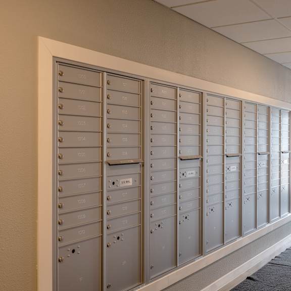 a row of lockers in a hallway with an exit door at technology park apartments, rochester, minnesota