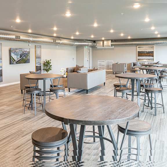 a communal area with tables and chairs in a large room at technology park apartments, rochester