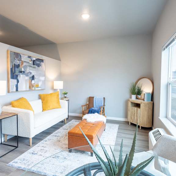 a living room with a couch and a coffee table and a large window at technology park apartments, rochester, minnesota