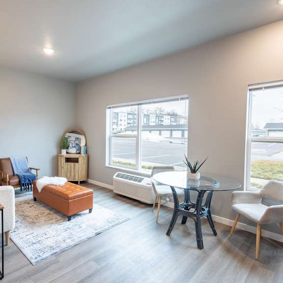 a living room with a table and chairs and a large window at technology park apartments, rochester, mn