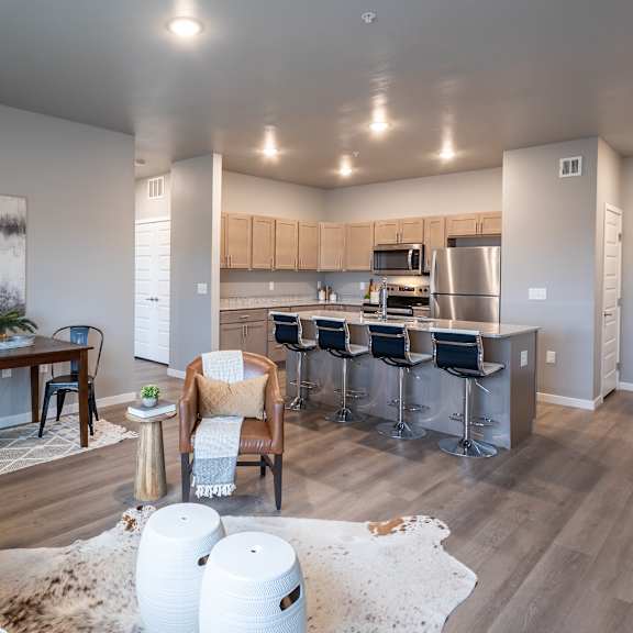 an open living room and kitchen with a dining room table and chairs at technology park apartments, rochester
