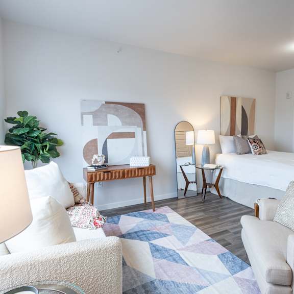 a bedroom with a bed and a living room with a couch and a chair at technology park apartments, minnesota, 55901