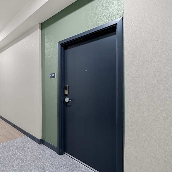 a long hallway with a black door on the right.