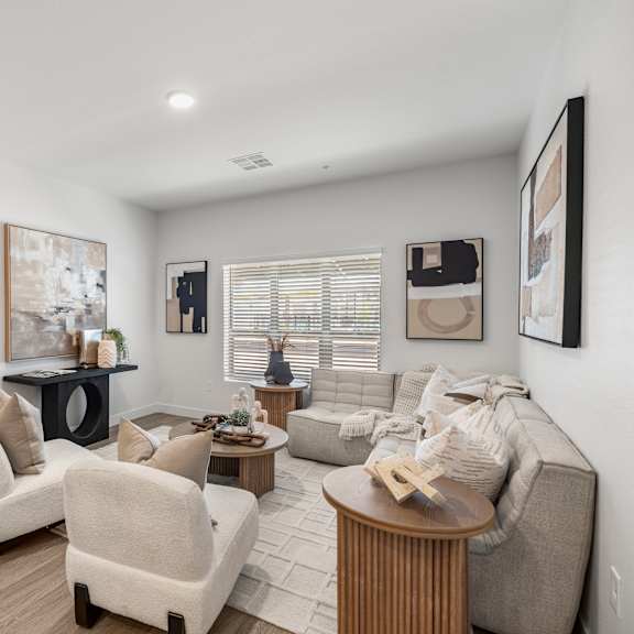 a living room with a grey couch, a coffee table, and a painting on the wall.