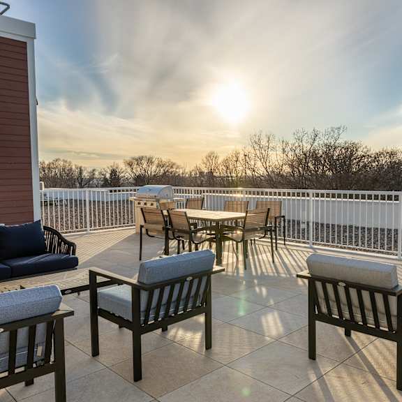 a patio with tables and chairs and a sunset in the background