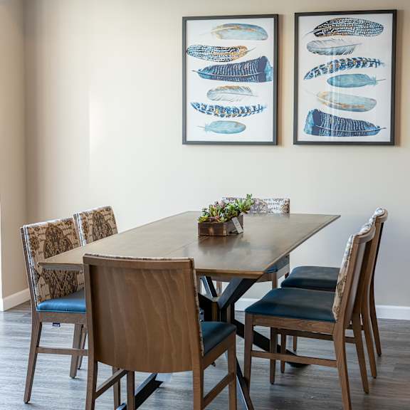 a dining room with a wooden table and chairs and two fish artwork on the wall
