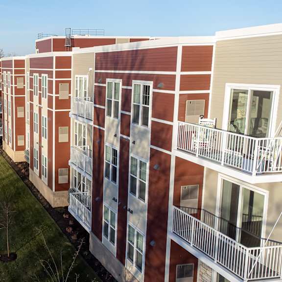 a row of red and white buildings with balconies and a road