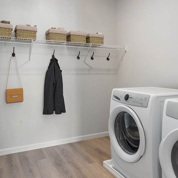 a washer and dryer in a laundry room with a white wall at the landing at amber fields apartments, rosemount, 55068