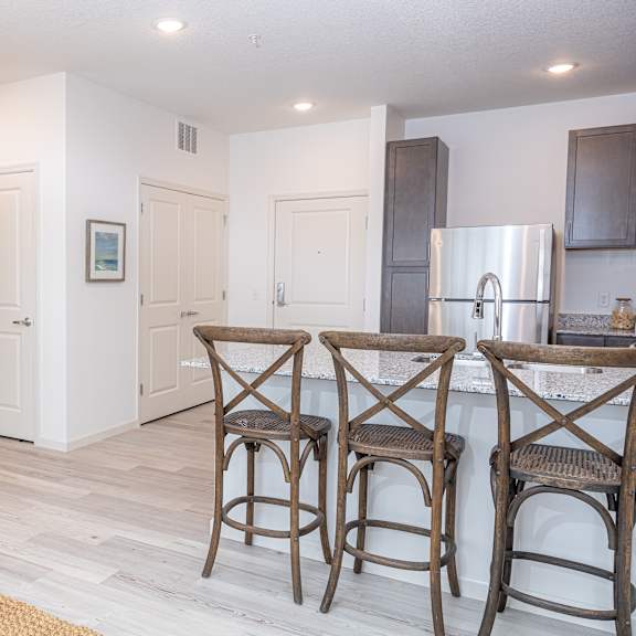 a living room with a kitchen and a bar with three stools