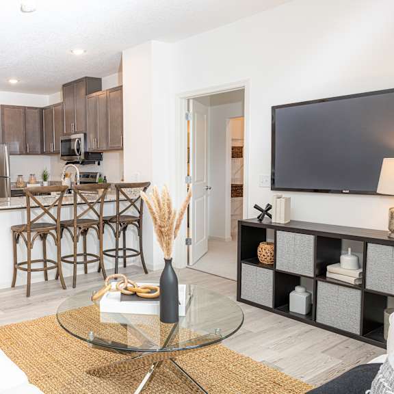 a living room with a kitchen with a bar and a television