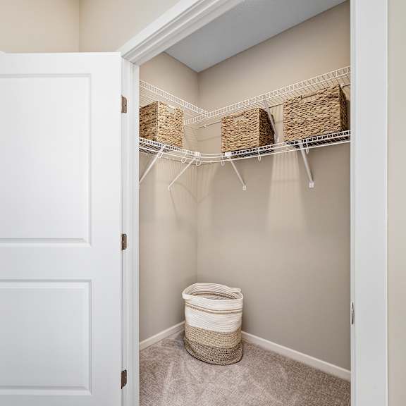 a white door is open to a bathroom with a toilet and storage baskets at the winslow 62+ apartments, minnesota