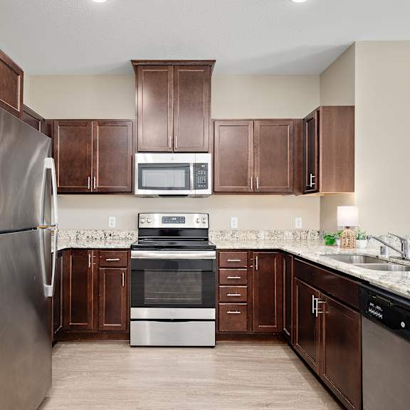 a kitchen with brown cabinets and a stainless steel refrigerator at the winslow 62+ apartments, west st paul, 55118