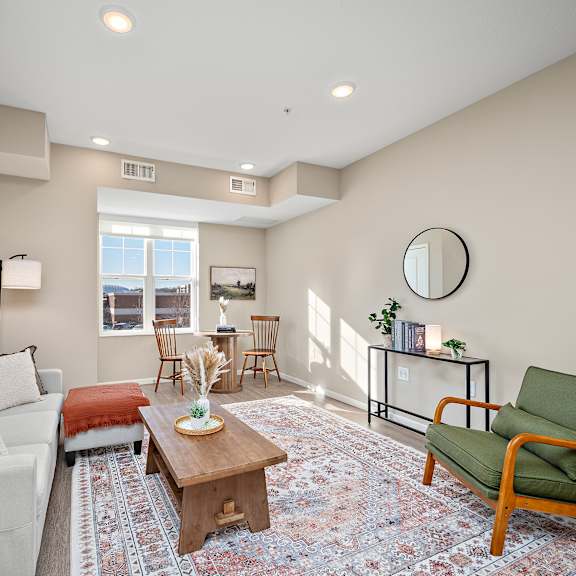 a living room with a white couch, a green chair, and a rug at the winslow 62+ apartments, west st paul