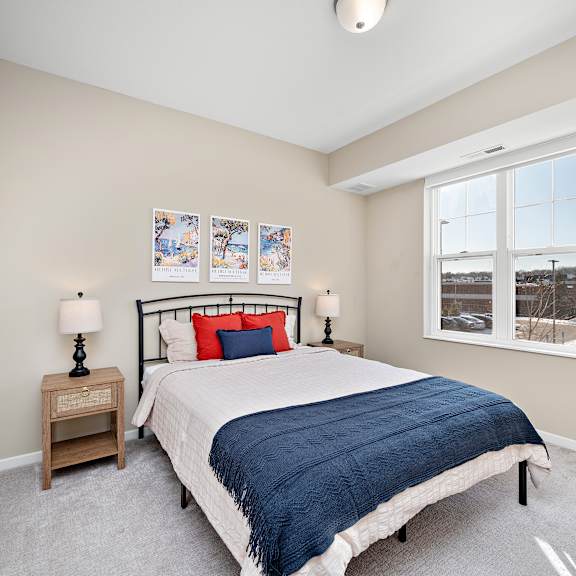 a bedroom with a bed, nightstand, and pictures on the wall at the winslow 62+ apartments, west st paul, mn, 55118