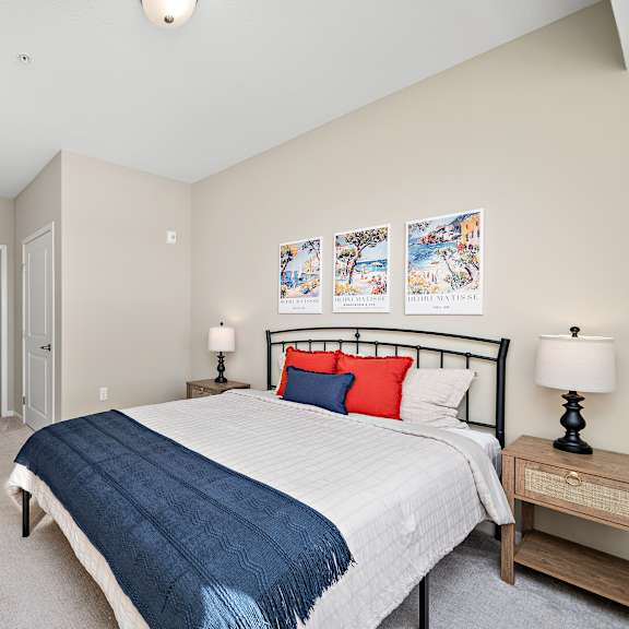 a bedroom with a bed, nightstand, and a painting on the wall at the winslow 62+ apartments, west st paul, mn