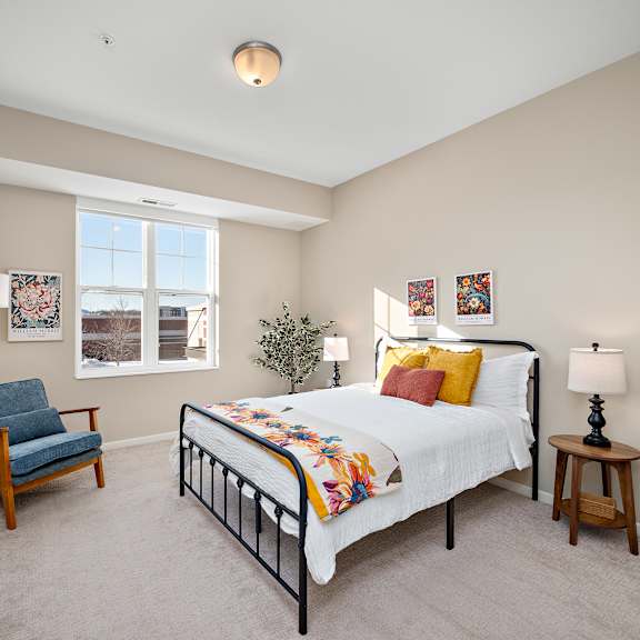 a bedroom with a bed, chair, and lamp at the winslow 62+ apartments, west st paul, minnesota