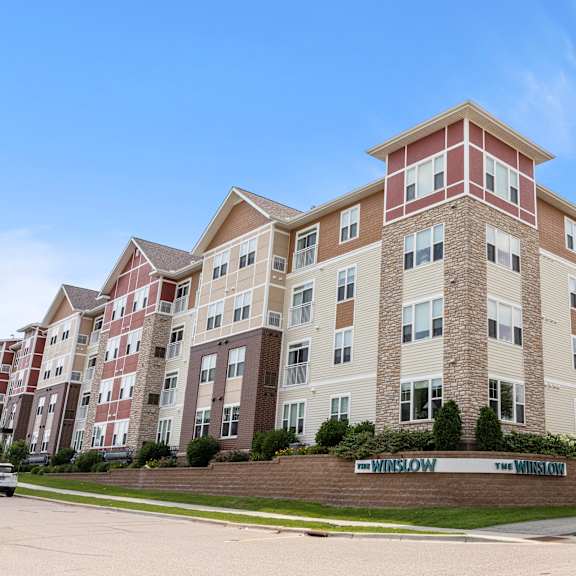 an apartment building on the corner of a street at the winslow 62+ apartments, west st paul, mn