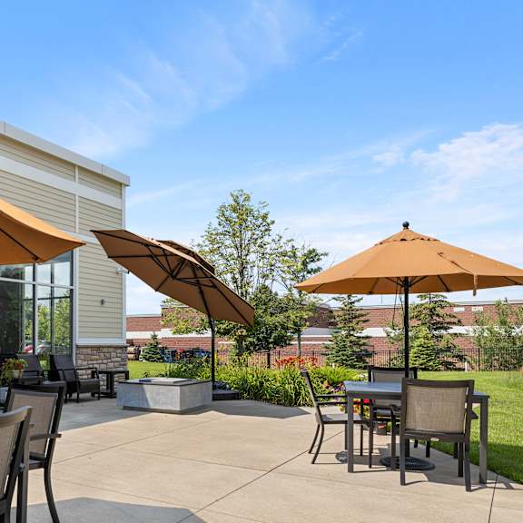 a patio with tables and umbrellas in front of a building at the winslow 62+ apartments, west st paul, mn, 55118